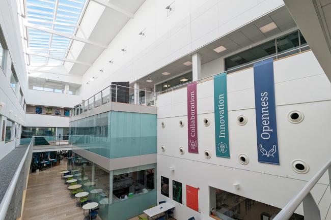 Inside the Earlham Institute atrium, with three large banners showcasing three of our values - collaboration, innovation, and openness.